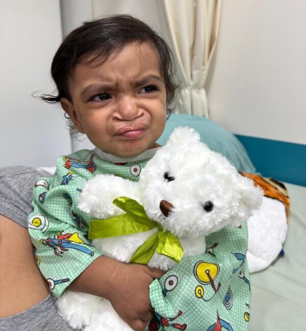 Child with cleft palate holding a white teddy bear in the hospital