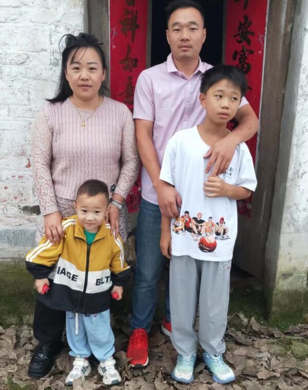 Two parent standing with two children in front of a red door